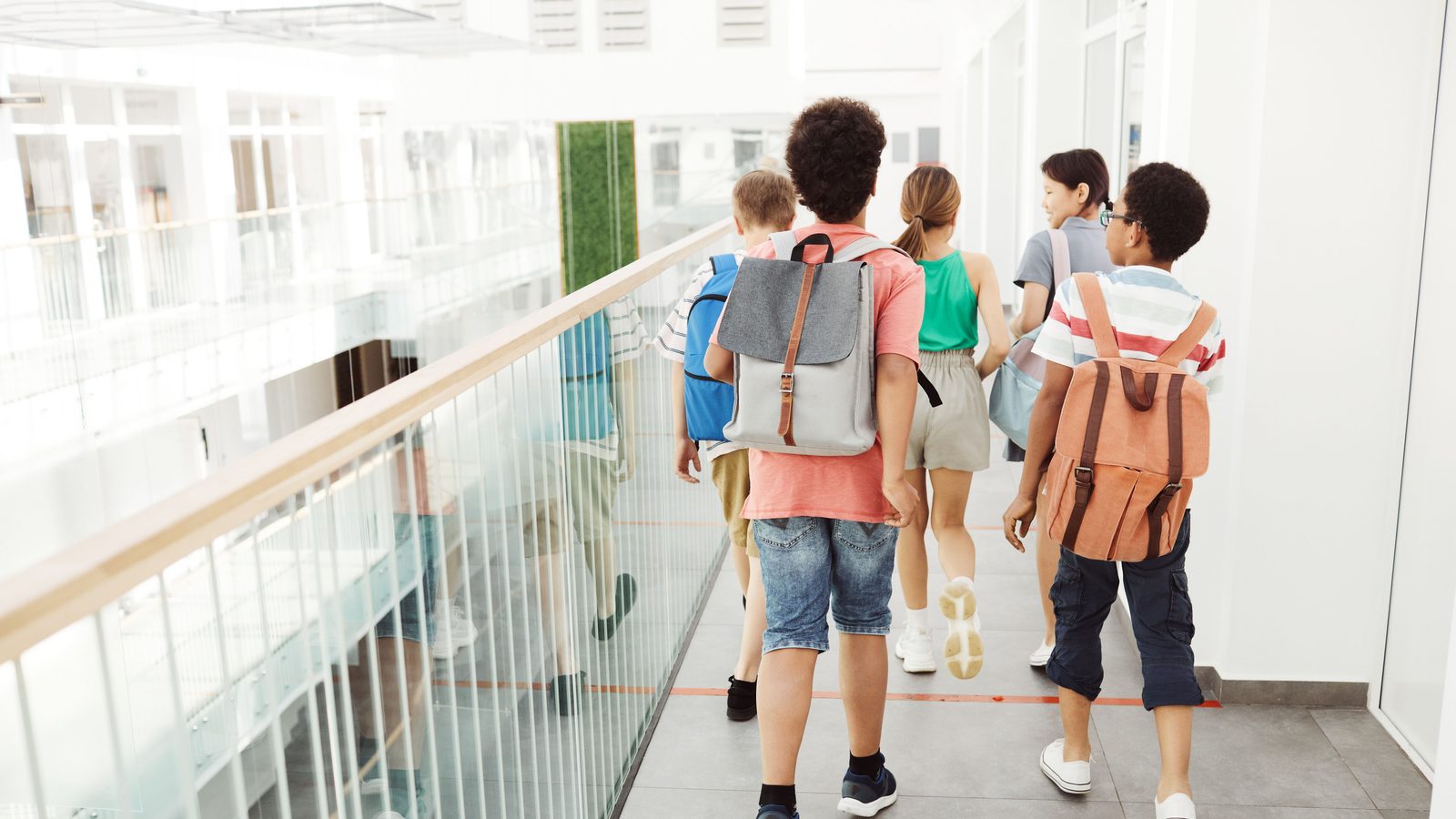 Des enfants marchent dans le couloir lumineux d'une école moderne.